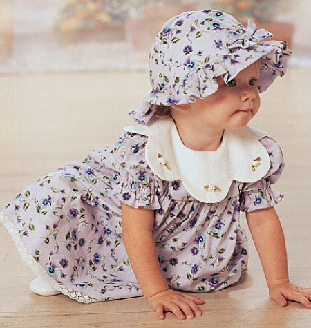 Petite fille en robe et bonnet à fleurs lavande, robe à manches bouffantes et col blanc à rabat, accentuée de dentelle.