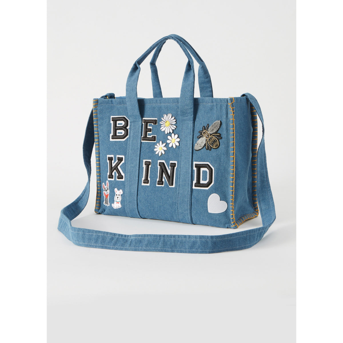 Sac en jean bleu avec broderies et patches “BE KIND”, grandes lettres noir et blanc, motifs fleurs, abeille, cœurs et animaux, poignées et bandoulière.