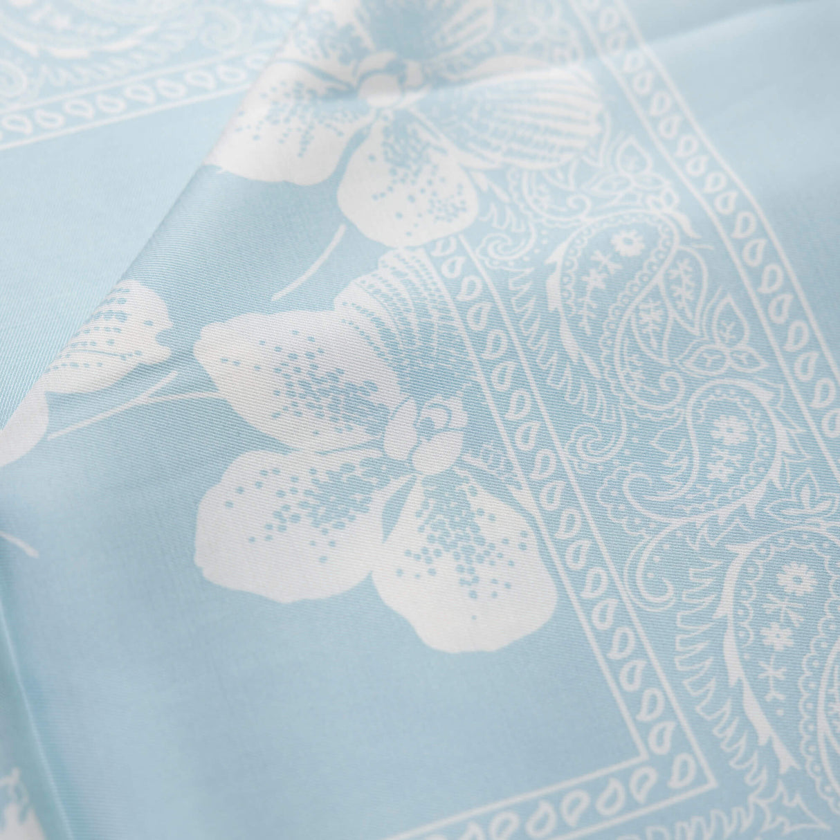 Twill 100% viscose – Fleurs blanches fond bleu ciel