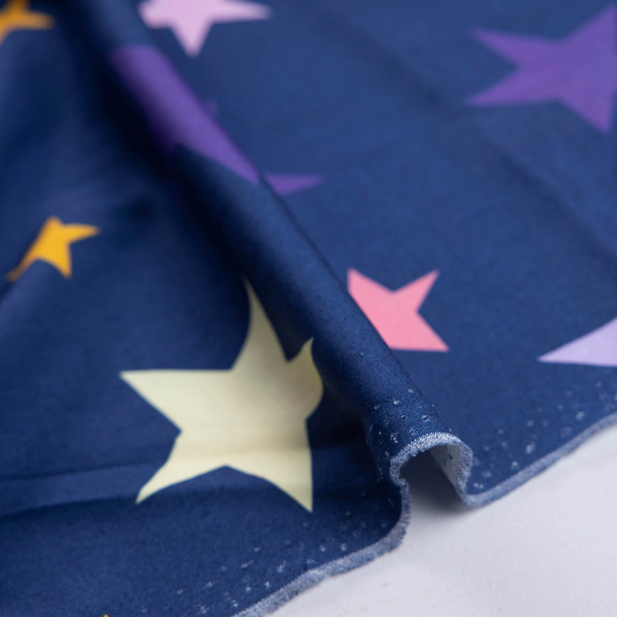 Étoffe 100% viscose - Étoiles multicolores fond bleu marine