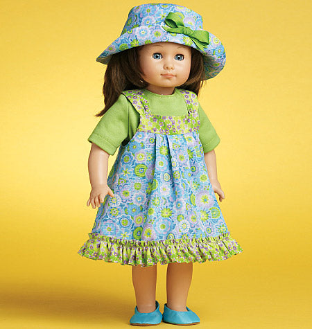 Une poupée garçon miniature porte une robe à fleurs bleu et vert avec volant à la base, accompagnée d’un chapeau bleu à fleurs et des chaussures turquoise.